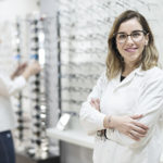 Posing optometrist woman in eyeglasses store smiling looking at